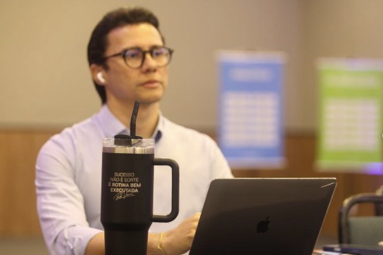 Natan Andrade conduzindo um trabalho em sala, com notebook e material de apoio.